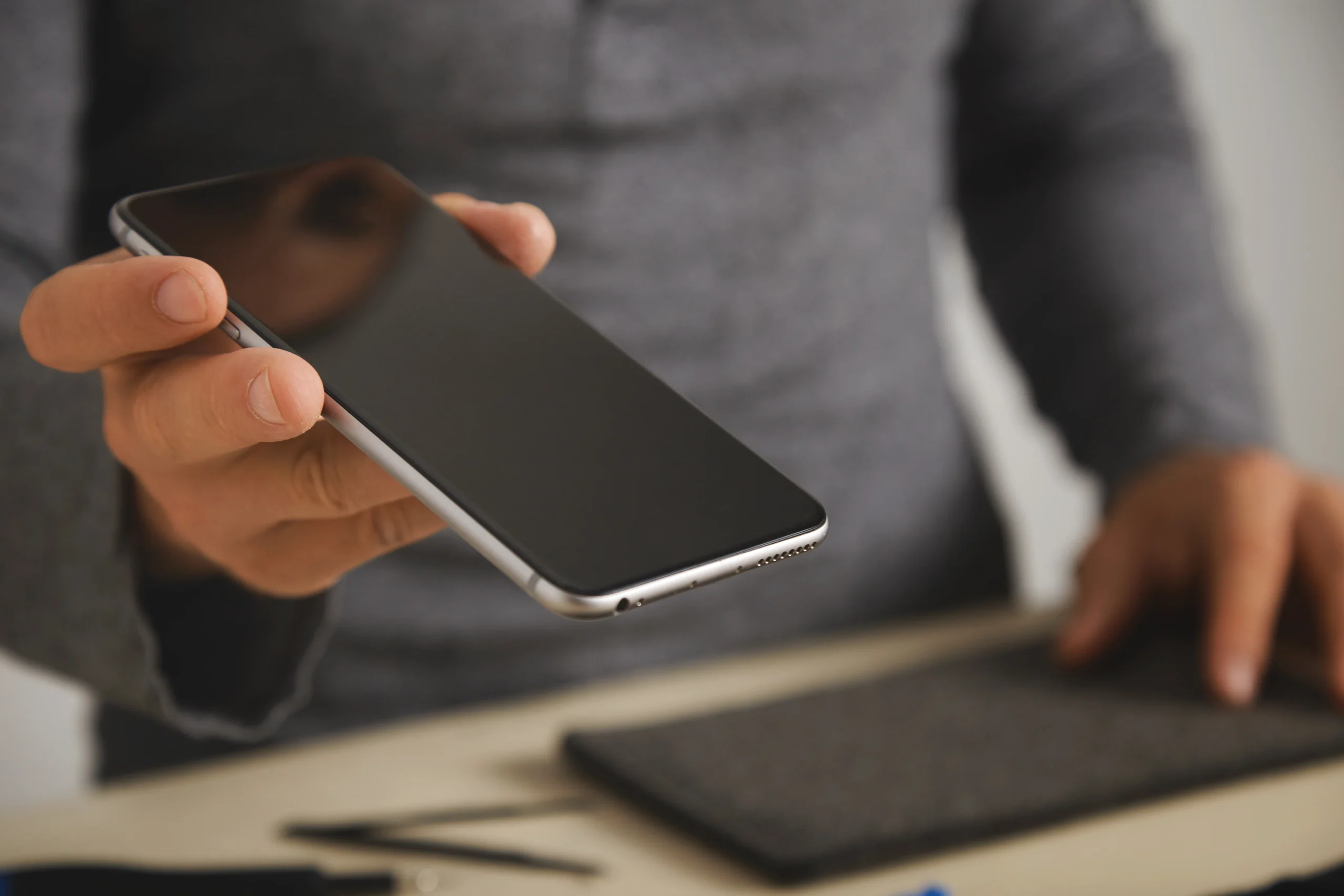 A person holding a smartphone against a bright window